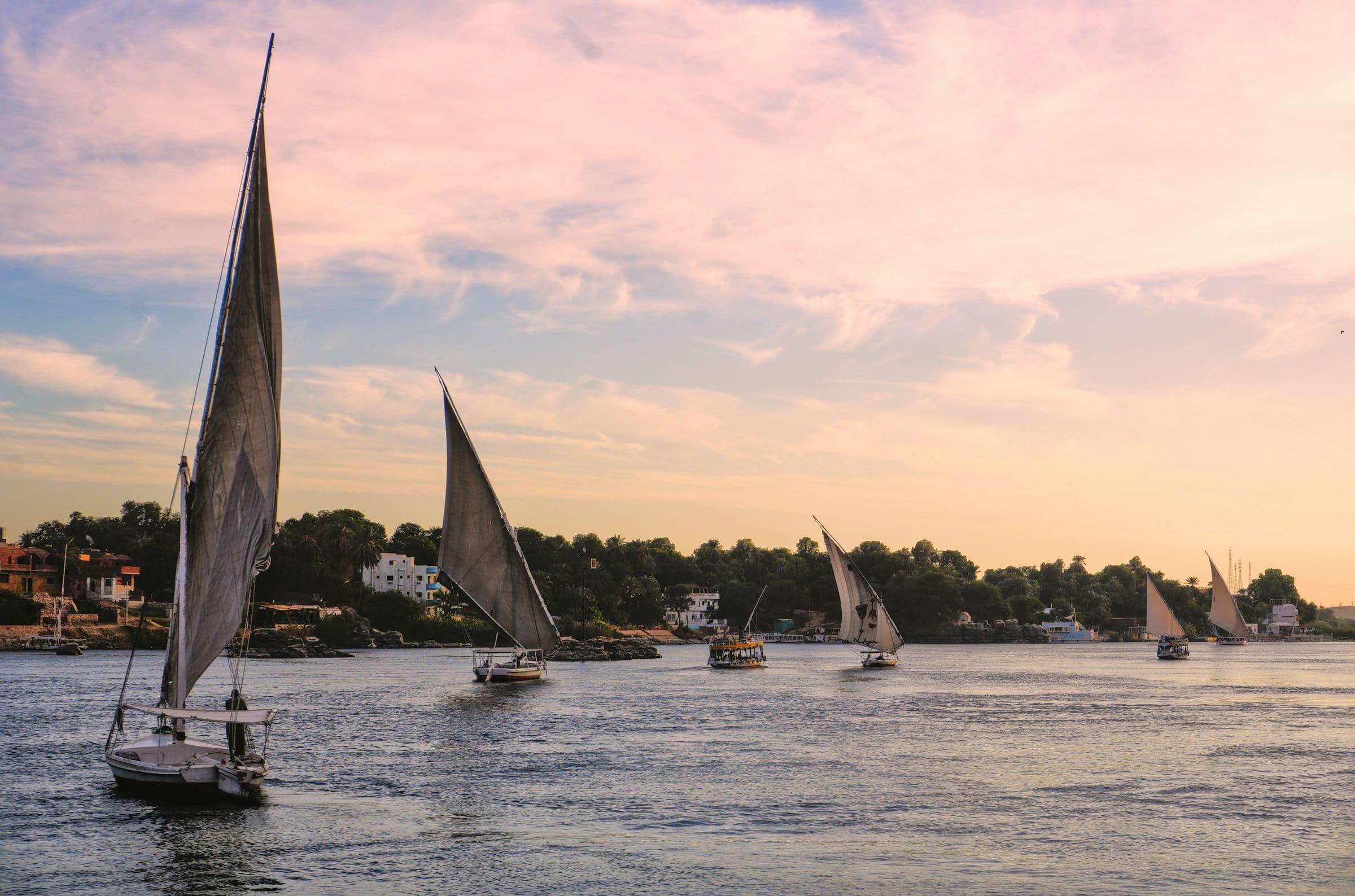 Feluccas gliding across the Nile at dusk